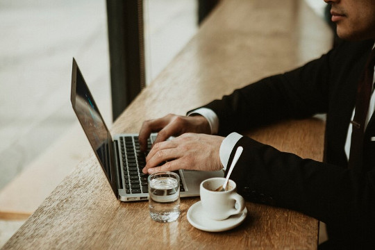 Un homme travaillant sur un ordinateur portable dans un café, symbolisant le télétravail nomade et les préoccupations de cybersécurité dans les espaces publics.