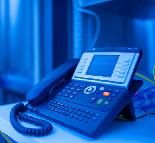 Bureau équipé de câbles de connexion et d'un téléphone fixe, illustrant une infrastructure de téléphonie VoIP dans un environnement professionnel.