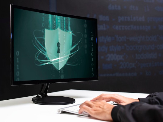 Personne devant un ordinateur affichant du code binaire, symbolisant la nécessité de renforcer la sécurité des données et d'adopter de bonnes pratiques d'hygiène numérique.